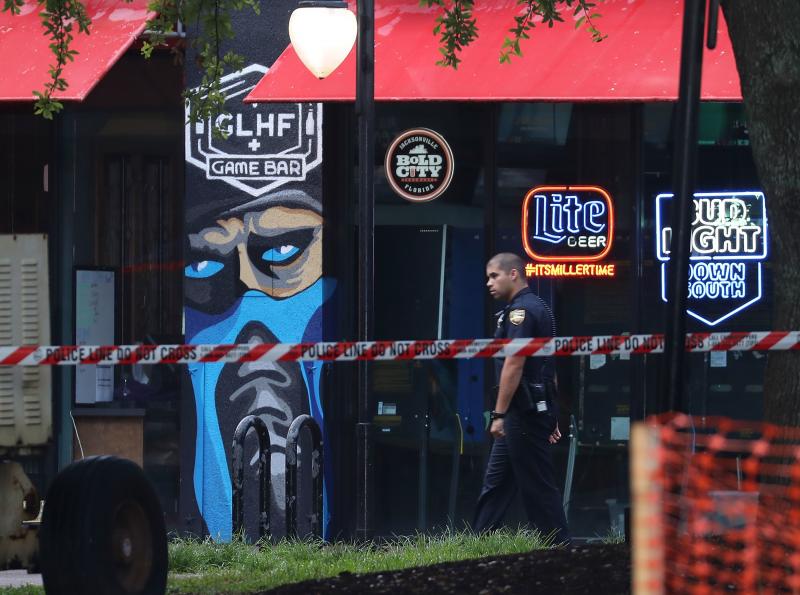 A police officer walks past the GLHF Game Bar where three people including the gunman were killed at Jacksonville Landing on Sunday in Jacksonville, Fla. A police officer walks past the GLHF Game Bar where three people including the gunman were killed at Jacksonville Landing on Sunday in Jacksonville, Fla.