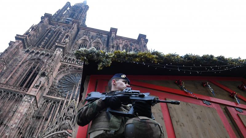 A French soldier stands guard at the Christmas market in Strasbourg, in front of the city's cathedral, as police conduct a search for a man suspected of opening fire on a crowd the night before. A French soldier stands guard at the Christmas market in Strasbourg, in front of the city's cathedral, as police conduct a search for a man suspected of opening fire on a crowd the night before.