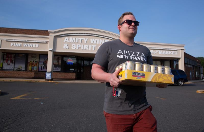 Adrián Rodriguez walks out of a liquor store in New Haven, Conn., with a 24-pack of Medalla Light. Adrián Rodriguez walks out of a liquor store in New Haven, Conn., with a 24-pack of Medalla Light.