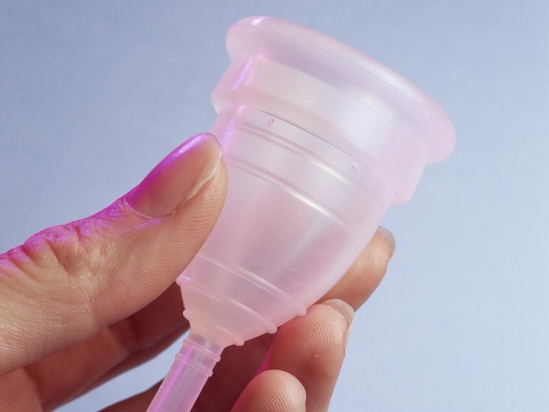 A menstrual cup — this one is made of silicone rubber — is designed to collect menstrual blood. The bell-shaped device is folded and inserted into the vagina. The tip helps with removal. A menstrual cup — this one is made of silicone rubber — is designed to collect menstrual blood. The bell-shaped device is folded and inserted into the vagina. The tip helps with removal.