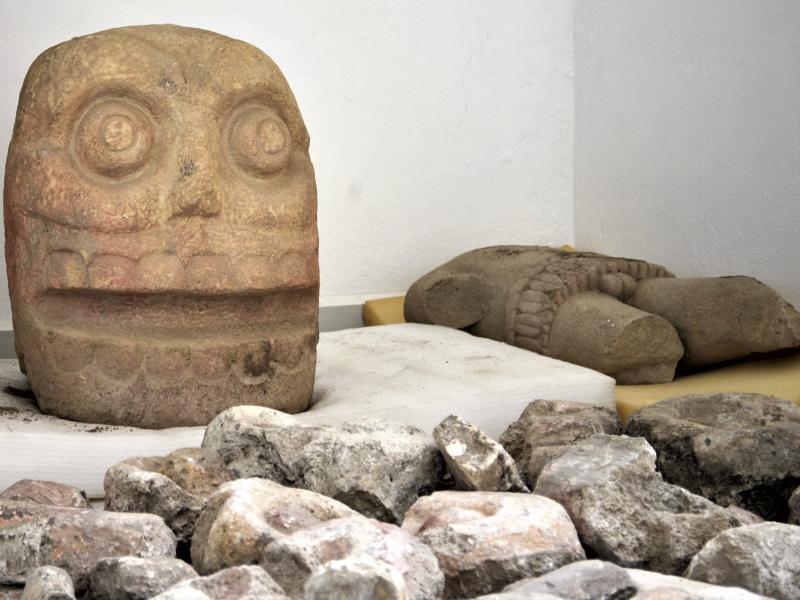A skull-like stone carving and a stone trunk depicting the Flayed Lord, a pre-Hispanic fertility god depicted as a skinned human corpse. A skull-like stone carving and a stone trunk depicting the Flayed Lord, a pre-Hispanic fertility god depicted as a skinned human corpse.