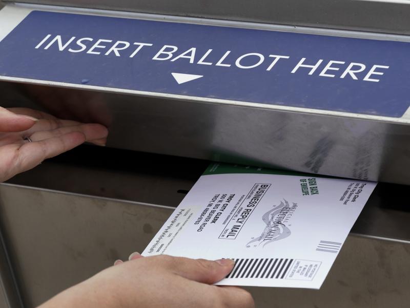 A voter is shown inserting her absentee voter ballot into a drop box earlier this month in Troy, Mich. A Michigan judge has blocked a ban on openly carrying guns in polling places on Election Day. A voter is shown inserting her absentee voter ballot into a drop box earlier this month in Troy, Mich. A Michigan judge has blocked a ban on openly carrying guns in polling places on Election Day.