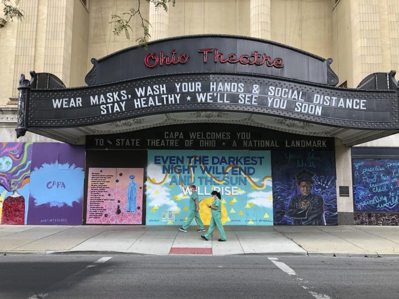 Workers in scrubs and masks walk past the Ohio Theatre in Columbus, Ohio last month amid the coronavirus pandemic. Workers in scrubs and masks walk past the Ohio Theatre in Columbus, Ohio last month amid the coronavirus pandemic.