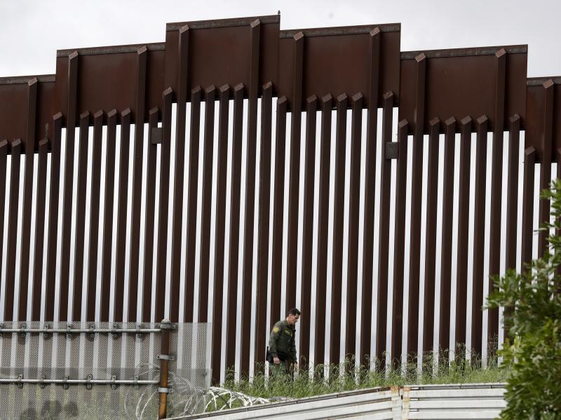 A Border Patrol agent walks along a border wall separating Tijuana, Mexico, from San Diego, in March 2020. A Border Patrol agent walks along a border wall separating Tijuana, Mexico, from San Diego, in March 2020.