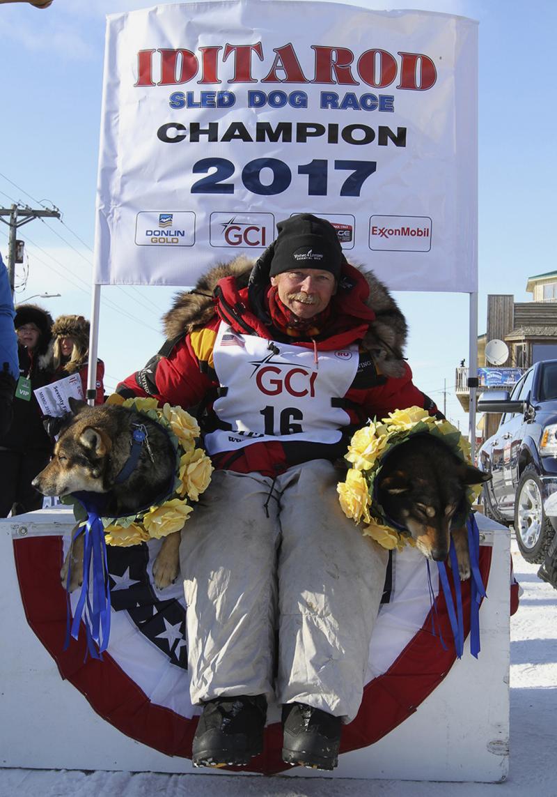 Mitch Seavey poses with his lead dogs Pilot, left, and Crisp under the Burled Arch after winning the 1,000-mile Iditarod Trail Sled Dog Race, in Nome, Alaska, on Tuesday. Seavey won his third Iditarod, becoming the fastest and oldest champion at age 57. Mitch Seavey poses with his lead dogs Pilot, left, and Crisp under the Burled Arch after winning the 1,000-mile Iditarod Trail Sled Dog Race, in Nome, Alaska, on Tuesday. Seavey won his third Iditarod, becoming the fastest and oldest champion at age 57.