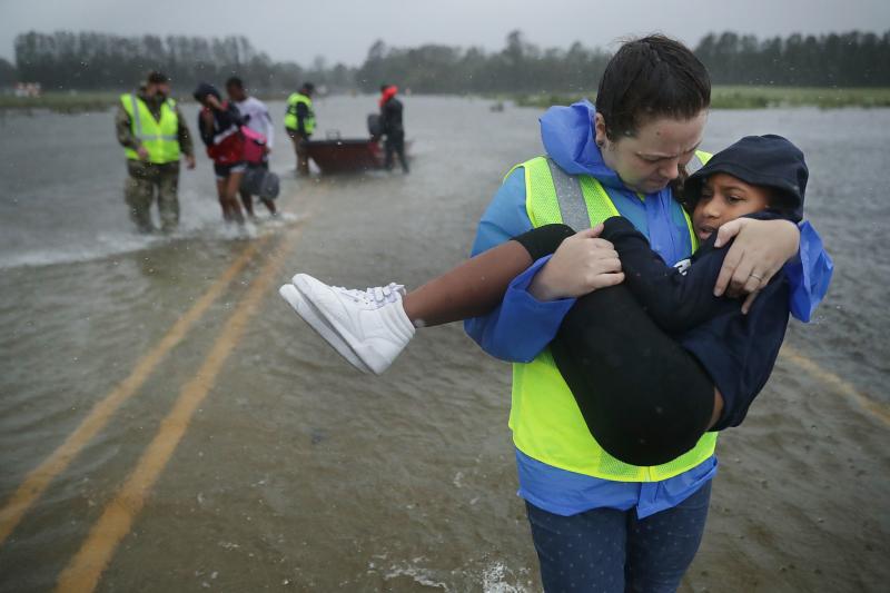 Volunteer Amber Hersel from the Civilian Crisis Response Team helps rescue Keiyana Cromartie, 7, and her family from their flooded home on Friday in James City, N.C., near New Bern. Volunteer Amber Hersel from the Civilian Crisis Response Team helps rescue Keiyana Cromartie, 7, and her family from their flooded home on Friday in James City, N.C., near New Bern.