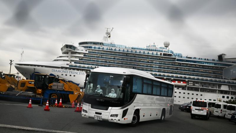 A bus departs from the dock where the Diamond Princess cruise ship sits under quarantine with its thousands of passengers and crew. Japanese authorities said Friday that some older passengers who tested negative for the coronavirus were allowed to disemba A bus departs from the dock where the Diamond Princess cruise ship sits under quarantine with its thousands of passengers and crew. Japanese authorities said Friday that some older passengers who tested negative for the coronavirus were allowed to disemba