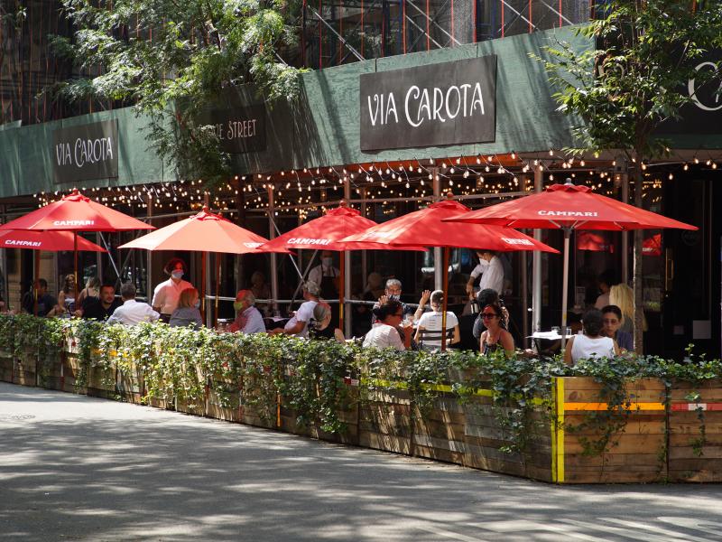 People dine under red umbrellas outside Via Carota restaurant in New York City's West Village. As the city continues to reopen, it is allowing restaurants to expand outdoors. People dine under red umbrellas outside Via Carota restaurant in New York City's West Village. As the city continues to reopen, it is allowing restaurants to expand outdoors.