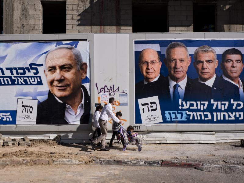 People walk by election campaign billboards in Tel Aviv, Israel, showing Israeli Prime Minister Benjamin Netanyahu (billboard on left) alongside the Blue and White alliance leaders (billboard on right, from left to right), Moshe Yaalon, Benny Gantz, Yair People walk by election campaign billboards in Tel Aviv, Israel, showing Israeli Prime Minister Benjamin Netanyahu (billboard on left) alongside the Blue and White alliance leaders (billboard on right, from left to right), Moshe Yaalon, Benny Gantz, Yair