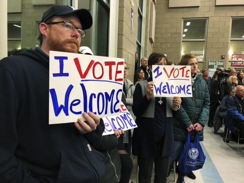 In this Dec. 9. 2019, file photo, residents in support of continued refugee resettlement hold signs at a meeting in Bismarck, N.D. In this Dec. 9. 2019, file photo, residents in support of continued refugee resettlement hold signs at a meeting in Bismarck, N.D.