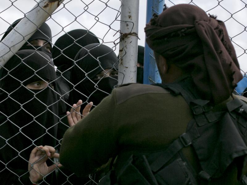 In this March 31, 2019, photo, women speak to guards at the gate that closes off the section for foreign families who lived in the Islamic State's so-called caliphate, at al-Hol camp in Hasakeh province, Syria. In this March 31, 2019, photo, women speak to guards at the gate that closes off the section for foreign families who lived in the Islamic State's so-called caliphate, at al-Hol camp in Hasakeh province, Syria.