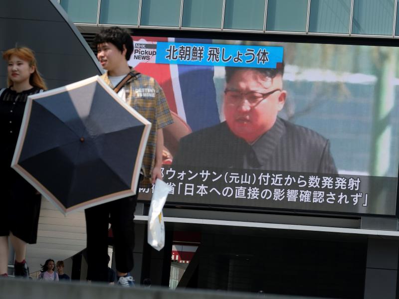 Pedestrians walk past a screen in Tokyo reporting about North Korea's test firing of a rocket system off the coast of North Korea on Wednesday. Pedestrians walk past a screen in Tokyo reporting about North Korea's test firing of a rocket system off the coast of North Korea on Wednesday.