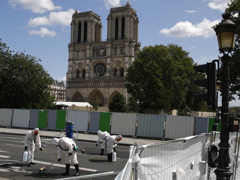 A cleanup crew scrubs pavement in front of the cathedral on Monday, after French inspectors said workers could return to the fire-damaged site to continue repairs. A cleanup crew scrubs pavement in front of the cathedral on Monday, after French inspectors said workers could return to the fire-damaged site to continue repairs.