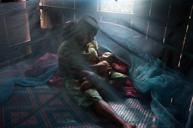 Yonta, 6, rests with her sister Montra, 3, and brother Leakhena, 4 months, under a mosquito bed net during monsoon season in July 2010, in Pailin province, Cambodia. Yonta, 6, rests with her sister Montra, 3, and brother Leakhena, 4 months, under a mosquito bed net during monsoon season in July 2010, in Pailin province, Cambodia.