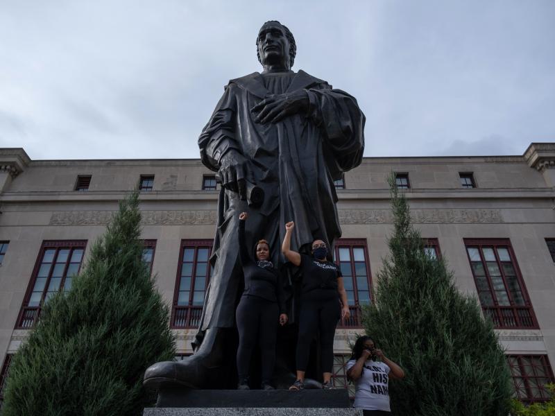 Demonstrators stand on the base of a Christopher Columbus statue in front of City Hall during a protest against police brutality Saturday in downtown Columbus, Ohio. Demonstrators stand on the base of a Christopher Columbus statue in front of City Hall during a protest against police brutality Saturday in downtown Columbus, Ohio.
