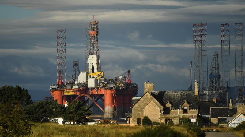 An oil rig towers over houses last week in Nigg, Scotland. Major players in the oil industry expect depressed oil demand and low prices to continue well into next year. An oil rig towers over houses last week in Nigg, Scotland. Major players in the oil industry expect depressed oil demand and low prices to continue well into next year.