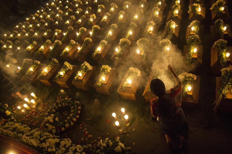 A woman spreads incense over the remains of 172 unidentified people who were discovered buried at what was once a Guatemalan military camp during the civil war in San Juan Comalapa, Guatemala, a day before their formal burial at the same site where they w A woman spreads incense over the remains of 172 unidentified people who were discovered buried at what was once a Guatemalan military camp during the civil war in San Juan Comalapa, Guatemala, a day before their formal burial at the same site where they w