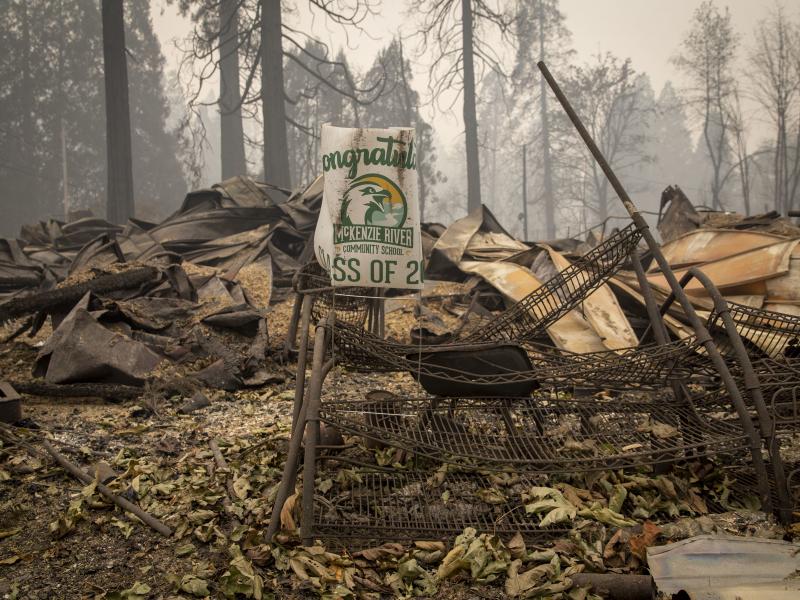 A sign for a recent graduate is bent but not burned in Blue River, Ore., eight days after the Holiday Farm Fire swept through its business district. A sign for a recent graduate is bent but not burned in Blue River, Ore., eight days after the Holiday Farm Fire swept through its business district.