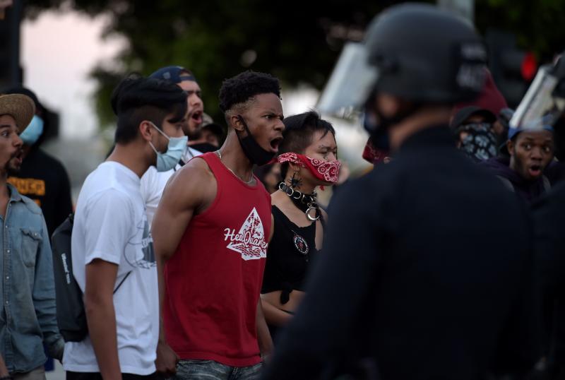 Protesters react in front of police as they gather in downtown Los Angeles on May 27, 2020 to demonstrate after George Floyd, an unarmed black man, died while being arrested by a police officer in Minneapolis who pinned him to the ground with his knee. Protesters react in front of police as they gather in downtown Los Angeles on May 27, 2020 to demonstrate after George Floyd, an unarmed black man, died while being arrested by a police officer in Minneapolis who pinned him to the ground with his knee.