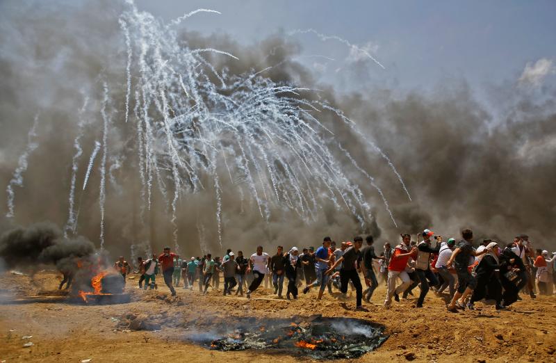Palestinians run for cover from tear gas during clashes with Israeli security forces near the border between Israel and the Gaza Strip. Palestinians run for cover from tear gas during clashes with Israeli security forces near the border between Israel and the Gaza Strip.