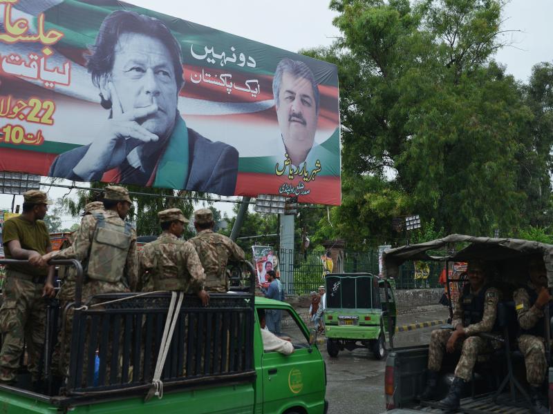 Pakistani soldiers patrol on a street beside a billboard featuring an image of Imran Khan of the Pakistan Tehreek-e-Insaf (Movement for Justice), in Rawalpindi. Pakistani soldiers patrol on a street beside a billboard featuring an image of Imran Khan of the Pakistan Tehreek-e-Insaf (Movement for Justice), in Rawalpindi.