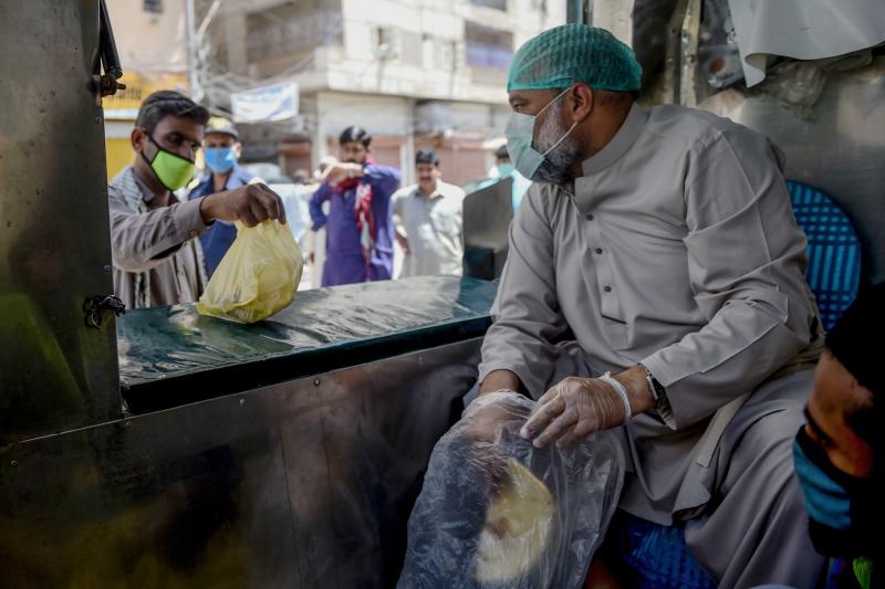 A municipal worker in Karachi hands out bags of food — part of government efforts to help those who've lost their livelihood during Pakistan's lockdown to stem the spread of the coronavirus. A municipal worker in Karachi hands out bags of food — part of government efforts to help those who've lost their livelihood during Pakistan's lockdown to stem the spread of the coronavirus.