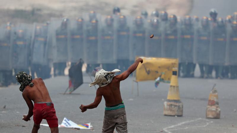 Demonstrators throw stones at a line of Venezuelan National Guard troops along Venezuela's border with Brazil, at the Brazilian city of Pacaraima on Sunday. Demonstrators throw stones at a line of Venezuelan National Guard troops along Venezuela's border with Brazil, at the Brazilian city of Pacaraima on Sunday.