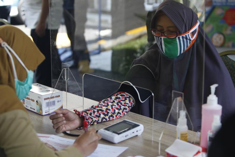 Health workers measure a woman's blood pressure during a simulation of a COVID-19 vaccine trial in Indonesia. Health workers measure a woman's blood pressure during a simulation of a COVID-19 vaccine trial in Indonesia.