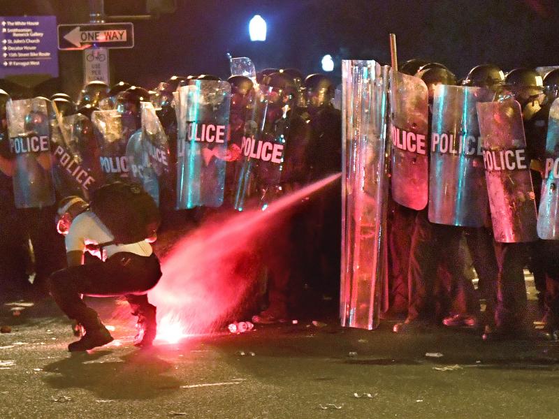 An anti-racism protester near Lafayette Square in Washington, D.C., in May is tear-gassed as he attempts to retrieve a flare thrown at police. An anti-racism protester near Lafayette Square in Washington, D.C., in May is tear-gassed as he attempts to retrieve a flare thrown at police.