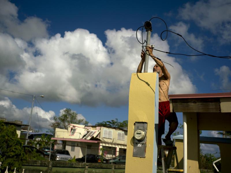 In a photograph taken in October, a resident tries to connect electrical lines downed by Hurricane Maria in preparation for when electricity is restored in Toa Baja, Puerto Rico. In a photograph taken in October, a resident tries to connect electrical lines downed by Hurricane Maria in preparation for when electricity is restored in Toa Baja, Puerto Rico.