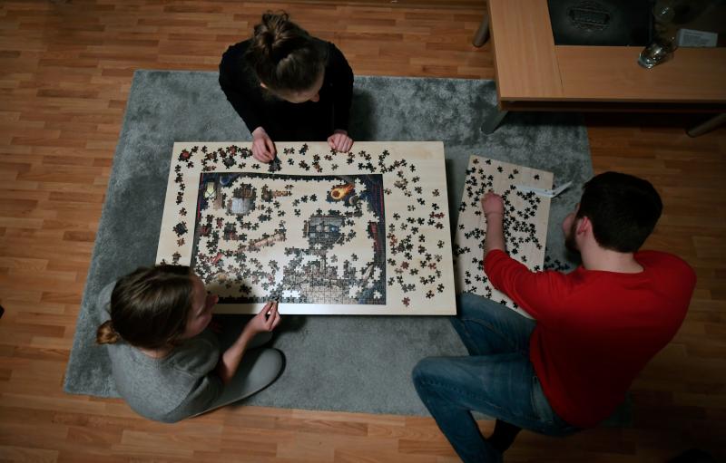 Flat-mates work on a puzzle in their living room in Dortmund, Germany, on March 27, 2020. Flat-mates work on a puzzle in their living room in Dortmund, Germany, on March 27, 2020.