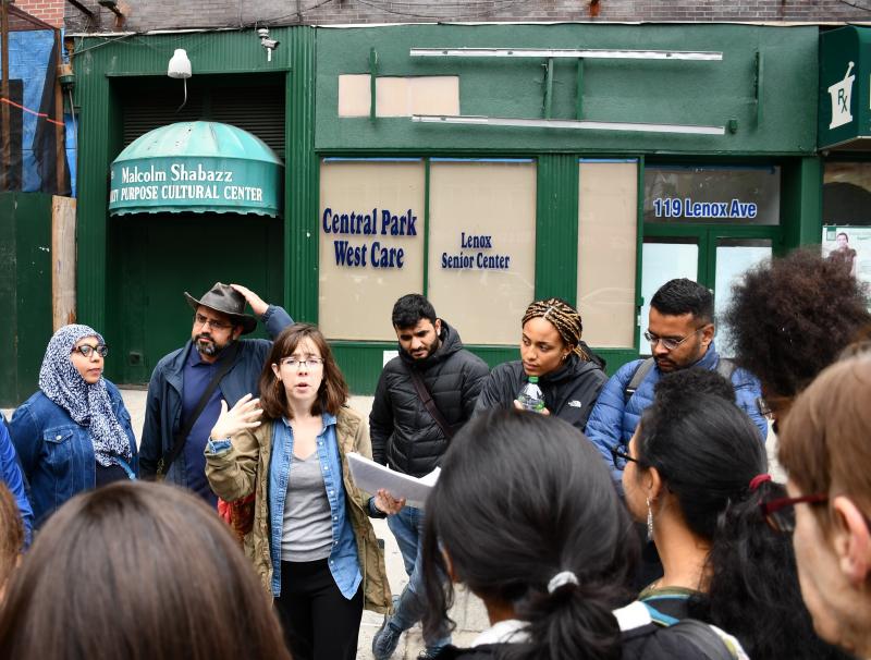 Tour participants listen to guide Katie Merriman (center) outside the Malcolm Shabaaz Mosque as she speaks about the influence of Malcolm X on the Harlem community. Tour participants listen to guide Katie Merriman (center) outside the Malcolm Shabaaz Mosque as she speaks about the influence of Malcolm X on the Harlem community.