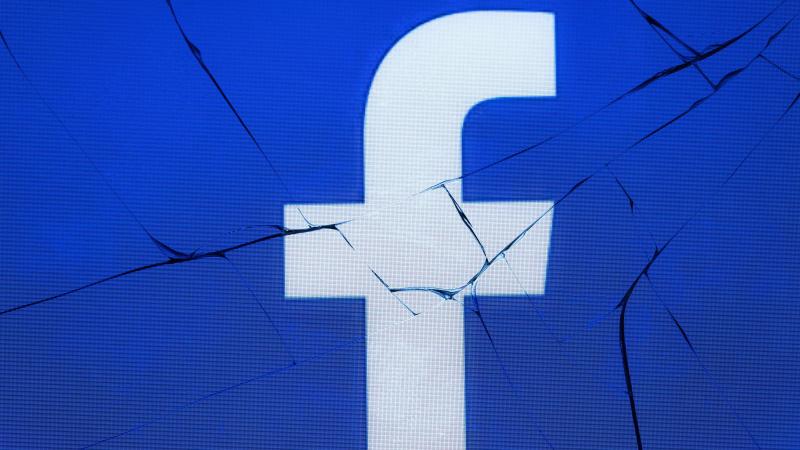 The logo of the social network Facebook appears on a broken screen of a mobile phone. The logo of the social network Facebook appears on a broken screen of a mobile phone.