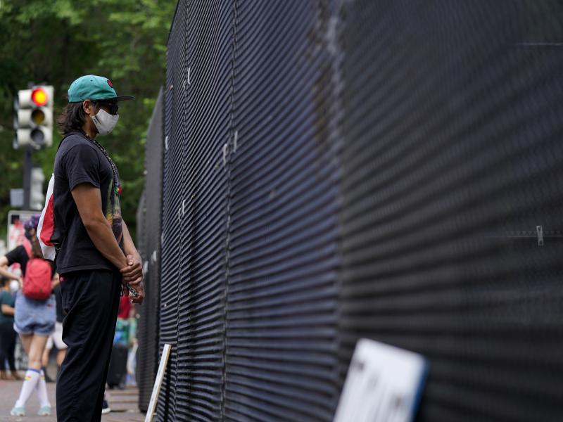 A person stands next to a fence as demonstrators protest Thursday near the White House over the death of George Floyd. The security perimeter is being extended several blocks. A person stands next to a fence as demonstrators protest Thursday near the White House over the death of George Floyd. The security perimeter is being extended several blocks.