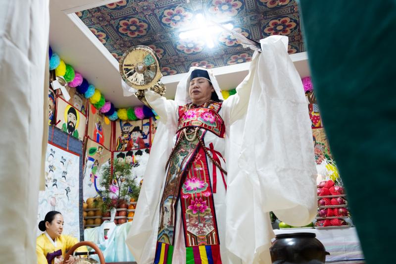 Shaman Jeong Soon-deok holds up a fan, bells and other ceremonial objects during an initiation ceremony at a temple in Seoul. Shaman Jeong Soon-deok holds up a fan, bells and other ceremonial objects during an initiation ceremony at a temple in Seoul.