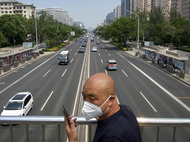 A man wearing a face mask stands on a bridge over an expressway in Beijing, Thursday, May 19, 2022. Parts of Beijing on Thursday halted daily mass testing that had been conducted over the past several weeks, but many testing sites remained busy due to req A man wearing a face mask stands on a bridge over an expressway in Beijing, Thursday, May 19, 2022. Parts of Beijing on Thursday halted daily mass testing that had been conducted over the past several weeks, but many testing sites remained busy due to req