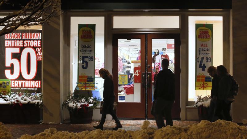 Shoppers in Freeport, Maine, pass by store windows advertising Black Friday deals after the stores opened their doors at midnight. Shoppers in Freeport, Maine, pass by store windows advertising Black Friday deals after the stores opened their doors at midnight.