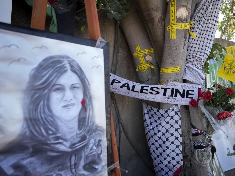 Yellow tape marks bullet holes on a tree and a portrait and flowers create a makeshift memorial on May 19, 2022, at the site where Palestinian-American Al-Jazeera journalist Shireen Abu Akleh was shot and killed in the West Bank city of Jenin. Yellow tape marks bullet holes on a tree and a portrait and flowers create a makeshift memorial on May 19, 2022, at the site where Palestinian-American Al-Jazeera journalist Shireen Abu Akleh was shot and killed in the West Bank city of Jenin.