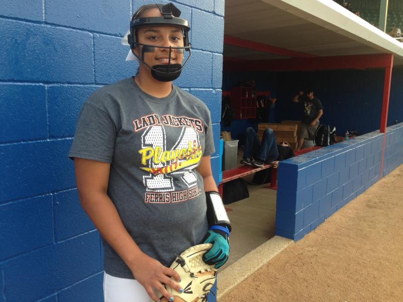 Ferris High School softball player Kylee Fowler stands beside the dugout, face mask on and ready. Ferris High School softball player Kylee Fowler stands beside the dugout, face mask on and ready.