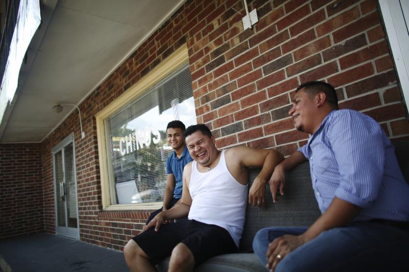 Joel Munguia (center), owner of Chino's, a barbershop in Kenner, La., sits with his nephew, Waldyn Munguia (left), as they have a laugh outside on the waiting benches at the shop. Munguia came to New Orleans from Honduras in 2005 after Katrina and opened Joel Munguia (center), owner of Chino's, a barbershop in Kenner, La., sits with his nephew, Waldyn Munguia (left), as they have a laugh outside on the waiting benches at the shop. Munguia came to New Orleans from Honduras in 2005 after Katrina and opened