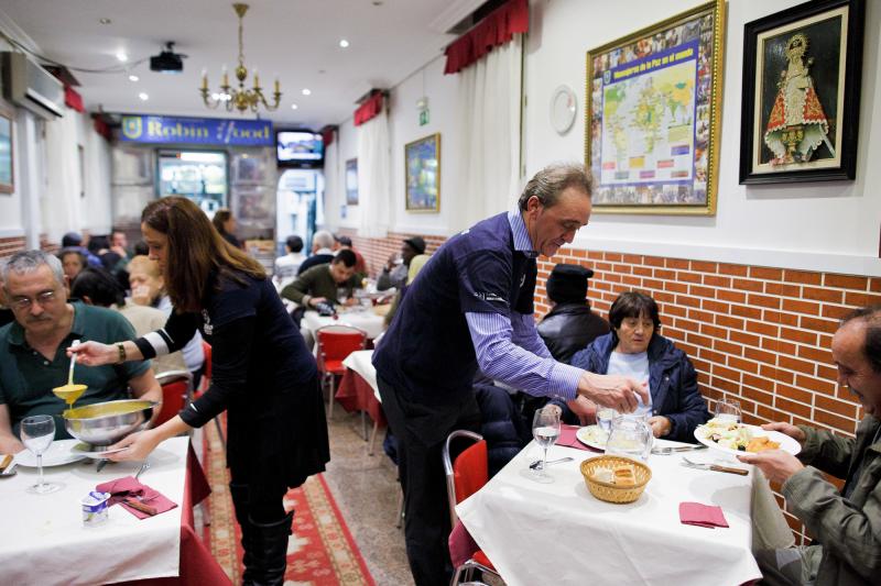 Volunteers serve free dinner to homeless people at Robin Hood restaurant in Madrid. Volunteers serve free dinner to homeless people at Robin Hood restaurant in Madrid.