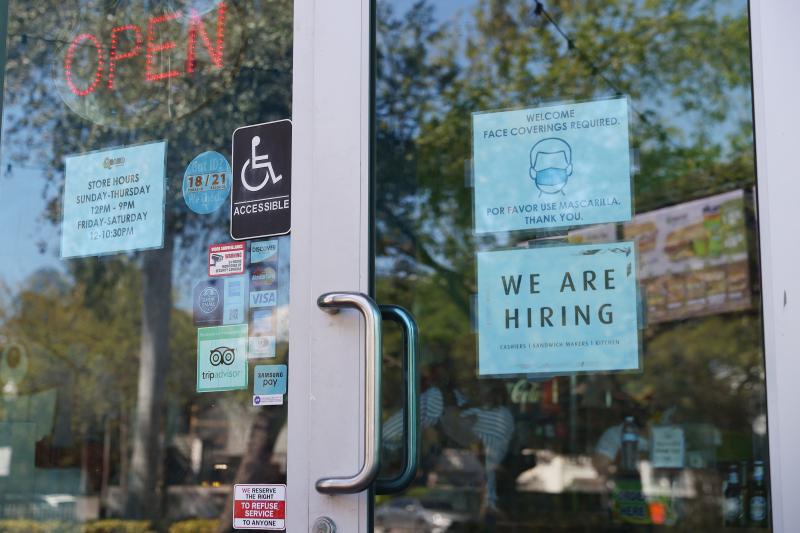 A "We are hiring" sign is paired with a pandemic-themed sign in the window of a store in Miami. Restaurants and other in-person businesses are looking to hire more workers at a time when some are wary of returning to work or are busy with caregiving. A "We are hiring" sign is paired with a pandemic-themed sign in the window of a store in Miami. Restaurants and other in-person businesses are looking to hire more workers at a time when some are wary of returning to work or are busy with caregiving.