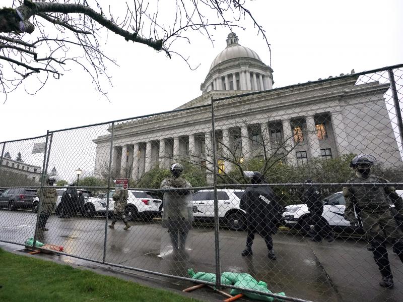 Members of the Washington National Guard stand near a fence surrounding the Capitol in Olympia, Wash., in anticipation of protests on Jan. 11, 2021. Members of the Washington National Guard stand near a fence surrounding the Capitol in Olympia, Wash., in anticipation of protests on Jan. 11, 2021.