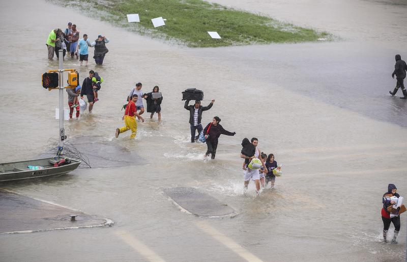 People walk down a flooded street as they evacuate their homes in Houston, Texas, on Monday. People walk down a flooded street as they evacuate their homes in Houston, Texas, on Monday.