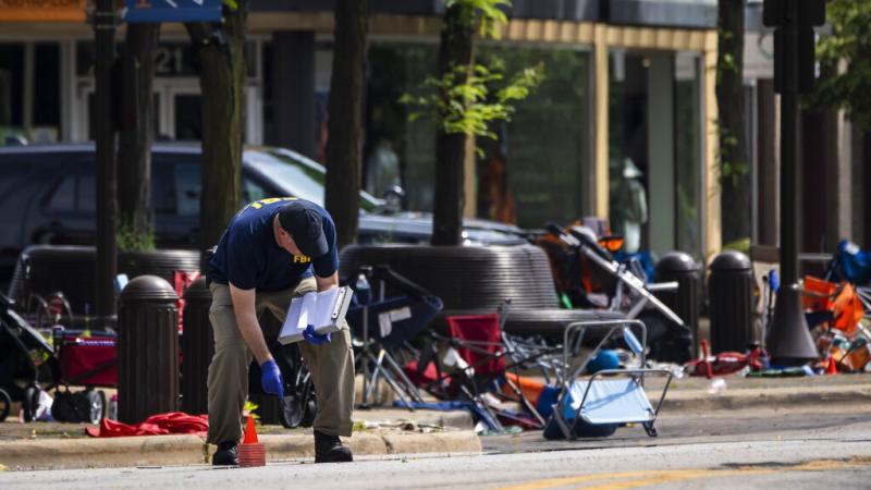 Members of the FBI's Evidence Response Team Unit investigate Tuesday in downtown Highland Park, Ill., the day after a deadly mass shooting. Police say the gunman who attacked an Independence Day parade in suburban Chicago fired more than 70 rounds with an Members of the FBI's Evidence Response Team Unit investigate Tuesday in downtown Highland Park, Ill., the day after a deadly mass shooting. Police say the gunman who attacked an Independence Day parade in suburban Chicago fired more than 70 rounds with an
