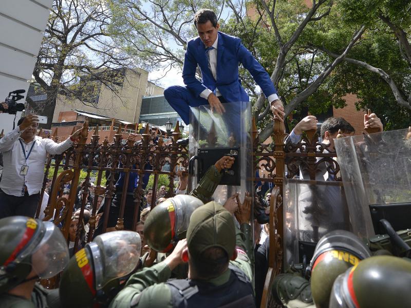 National Assembly President Juan Guaidó, Venezuela's opposition leader, climbs the fence in a failed attempt to enter the compound of the Assembly, as he and other opposition lawmakers are blocked from entering. National Assembly President Juan Guaidó, Venezuela's opposition leader, climbs the fence in a failed attempt to enter the compound of the Assembly, as he and other opposition lawmakers are blocked from entering.