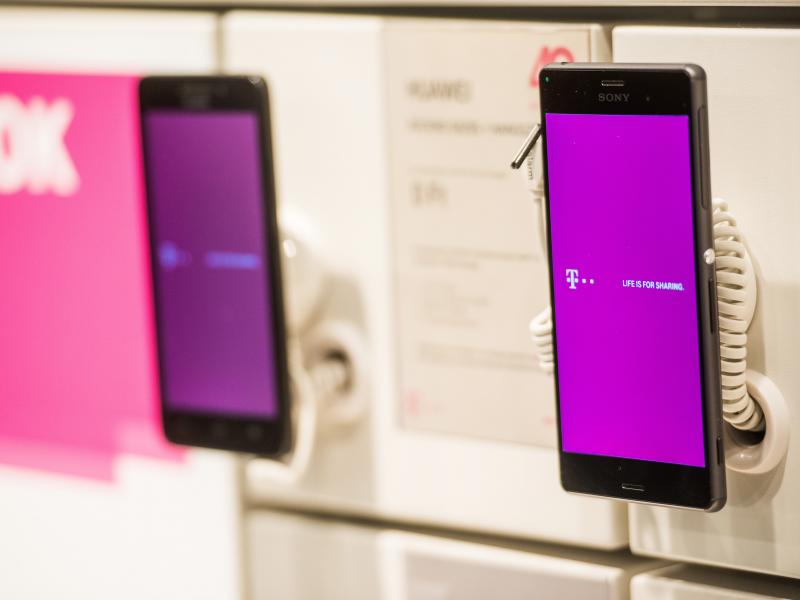A T-Mobile logo is displayed on a phone at a T-Mobile store. A T-Mobile logo is displayed on a phone at a T-Mobile store.
