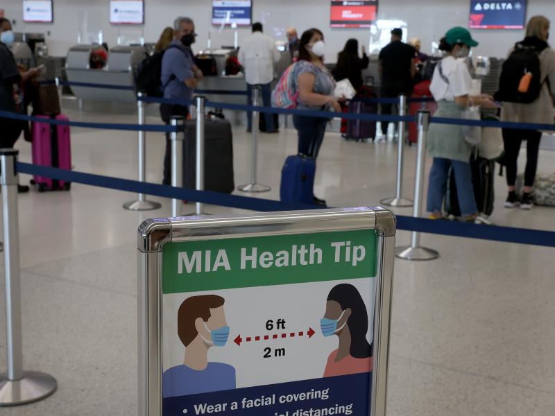 A sign advises people to wear a mask and stand six feet apart as travelers make their way through Miami International Airport in December 2021 in Miami. A federal judge in Florida has ruled that the federal mask mandate on planes, trains, buses and other A sign advises people to wear a mask and stand six feet apart as travelers make their way through Miami International Airport in December 2021 in Miami. A federal judge in Florida has ruled that the federal mask mandate on planes, trains, buses and other