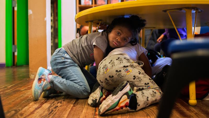 Justice Buress, 4, hides under a table while demonstrating a drill at Little Explorers Learning Center in St. Louis. Tess Trice, head of the day care program, carries out monthly drills to train the children to get on the floor when they hear gunfire. Justice Buress, 4, hides under a table while demonstrating a drill at Little Explorers Learning Center in St. Louis. Tess Trice, head of the day care program, carries out monthly drills to train the children to get on the floor when they hear gunfire.