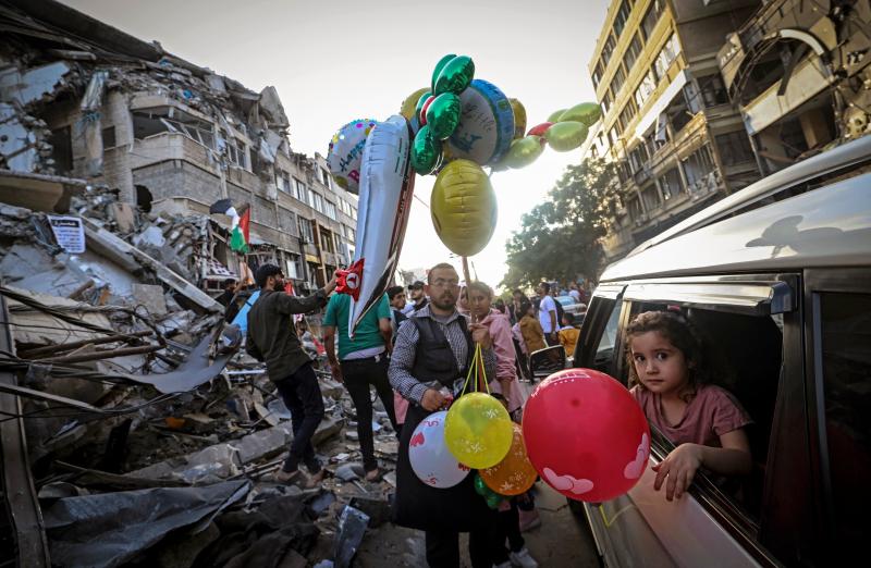 A Palestinian man sells balloons on Friday in Gaza City in front of the Al-Shuruq building, which was destroyed by an Israeli air strike. A Palestinian man sells balloons on Friday in Gaza City in front of the Al-Shuruq building, which was destroyed by an Israeli air strike.